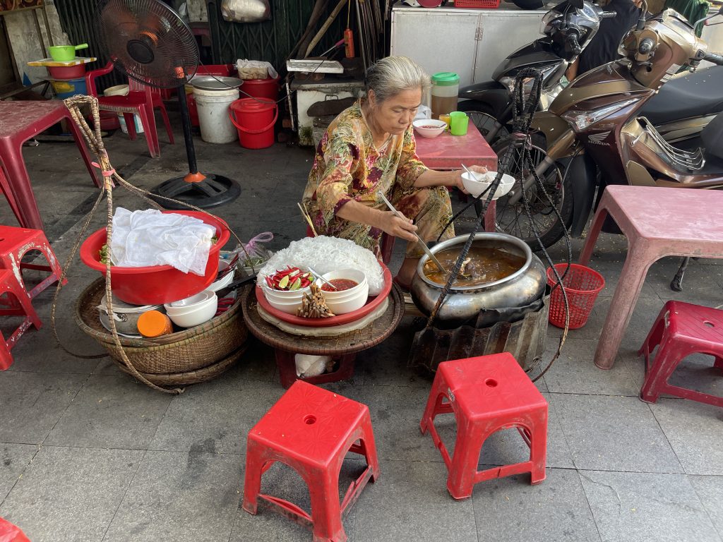 Venditrice vietnamita prepara zuppa tradizionale. Viaggio Vietnam: scopri sapori autentici!