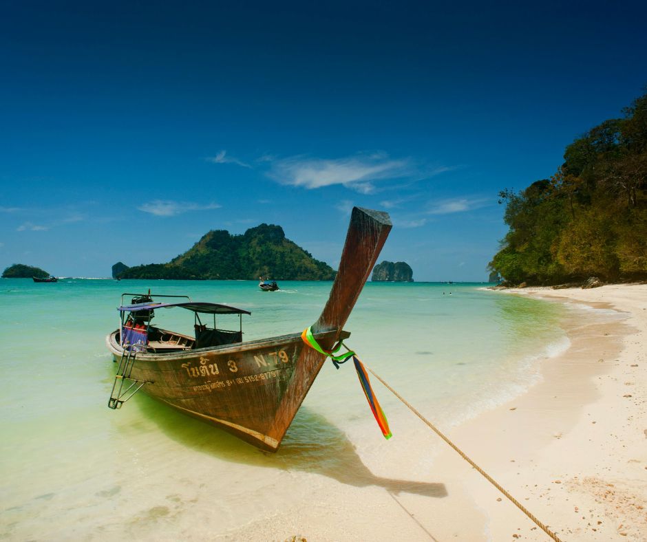 Thailandia: Barca tradizionale su spiaggia bianca. Vacanze di Natale e Capodanno esotiche.